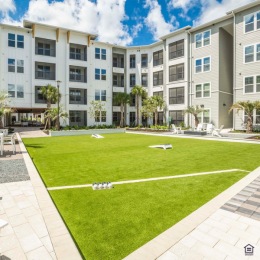 State of the art amenities Interior courtyard at Rosalia Winter Park apartments in Winter Park, FL, featuring outdoor games, chairs, and palm trees.