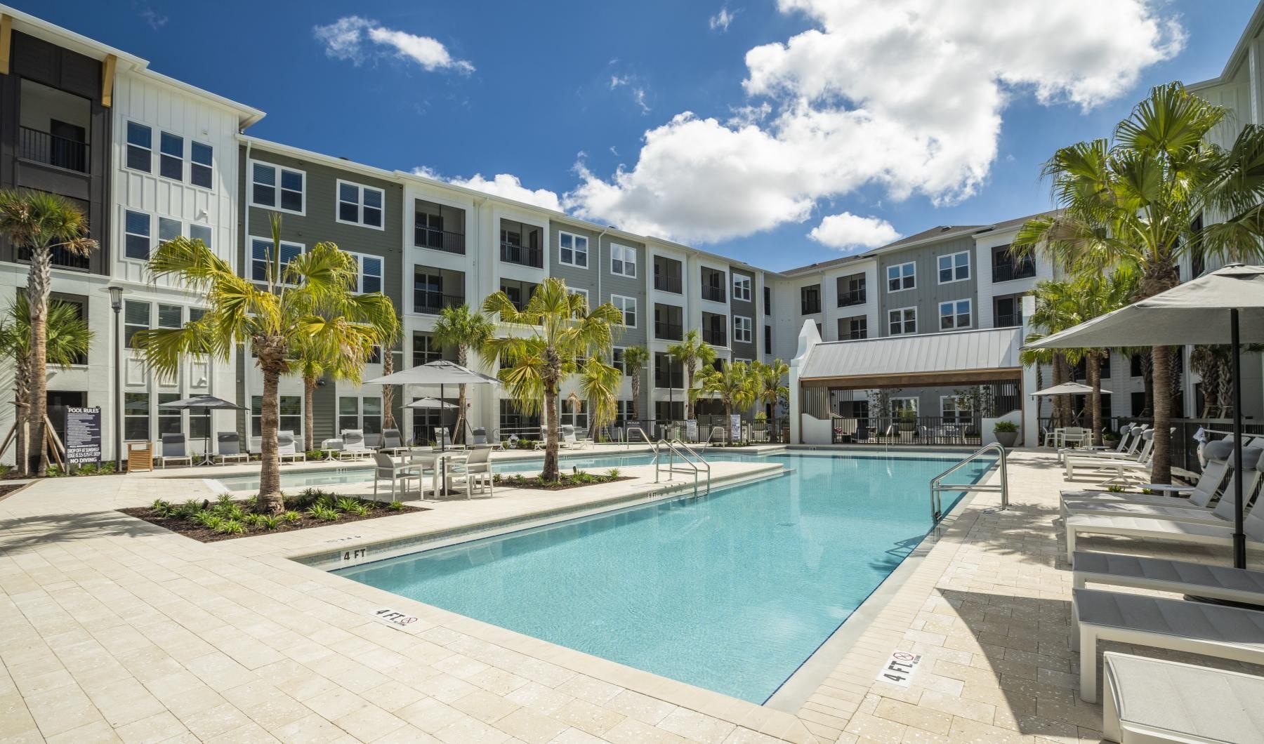 Resort-style swimming pool Outdoor swimming pool at Rosalia Winter Park apartments in Winter Park, FL, featuring lounge chairs and palm trees.
